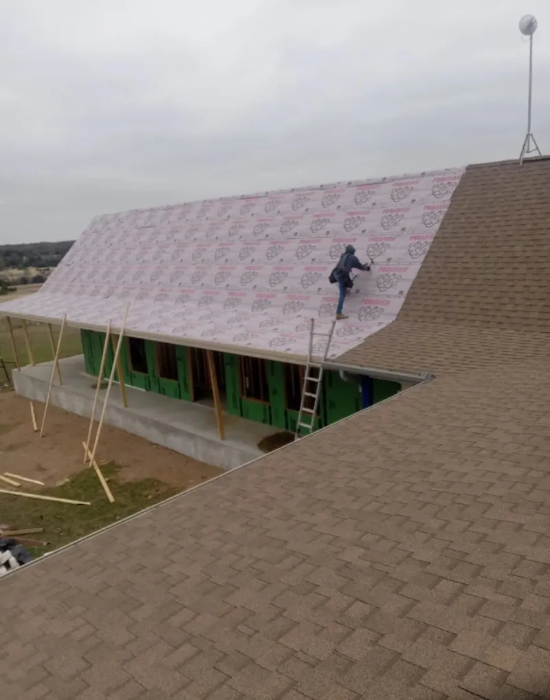 Worker preparing underlayment for a metal roof installation in Folcroft